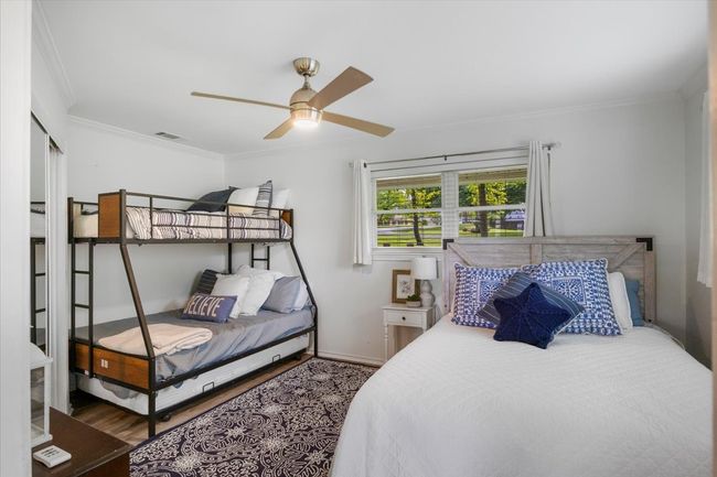 Bedroom with visible vents, baseboards, ornamental molding, wood finished floors, and a ceiling fan | Image 25
