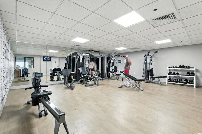 Workout area with a paneled ceiling and wood finished floors | Image 27