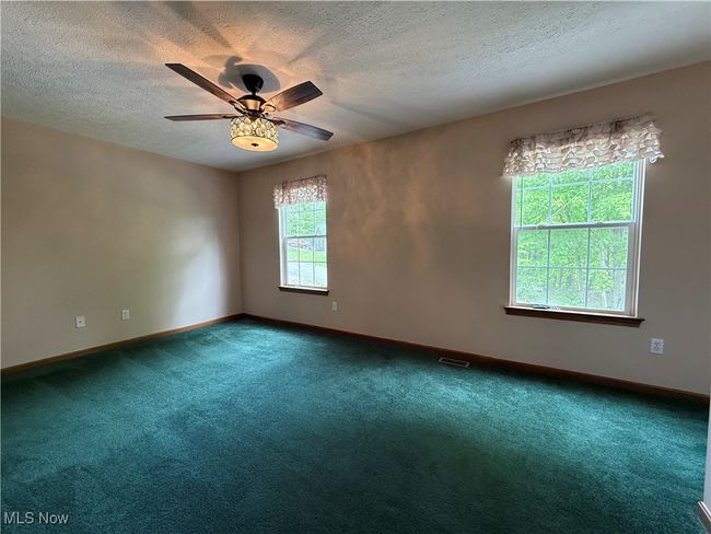 Carpeted spare room with a textured ceiling, ceiling fan, and baseboards | Image 30
