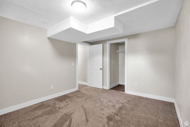 Unfurnished bedroom with a closet, baseboards, a textured ceiling, and carpet floors | Image 22