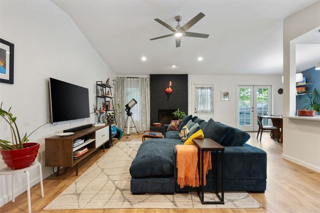 Living area featuring recessed lighting, lofted ceiling, wood finished floors, a brick fireplace, and ceiling fan | Image 6
