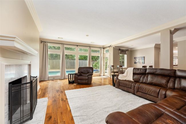 Anchored by a beautiful fireplace and framed with detailed crown molding, the living room features a full wall of windows overlooking the backyard and pool—bringing the outdoors in and adding a serene backdrop to your everyday moments. | Image 10