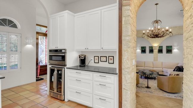 Kitchen featuring stainless steel microwave oven, wine cooler, and arched walkways | Image 18