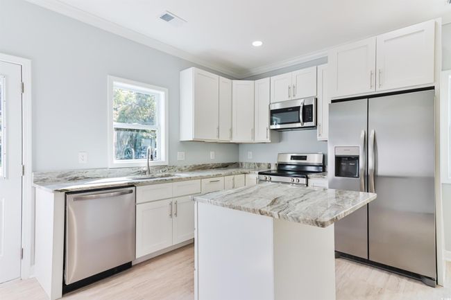 Kitchen with appliances with stainless steel finishes, a center island, white cabinetry, and sink | Image 7