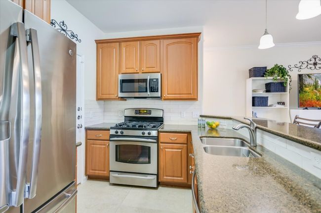 Kitchen with stainless steel appliances, dark stone countertops, tasteful backsplash, ornamental molding, and pendant lighting | Image 8