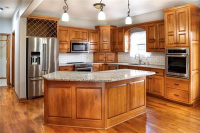 Kitchen featuring appliances with stainless steel finishes, hanging light fixtures, and light hardwood / wood-style flooring | Image 3