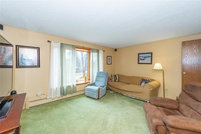 Living area with carpet, a textured ceiling, and a baseboard radiator | Image 14