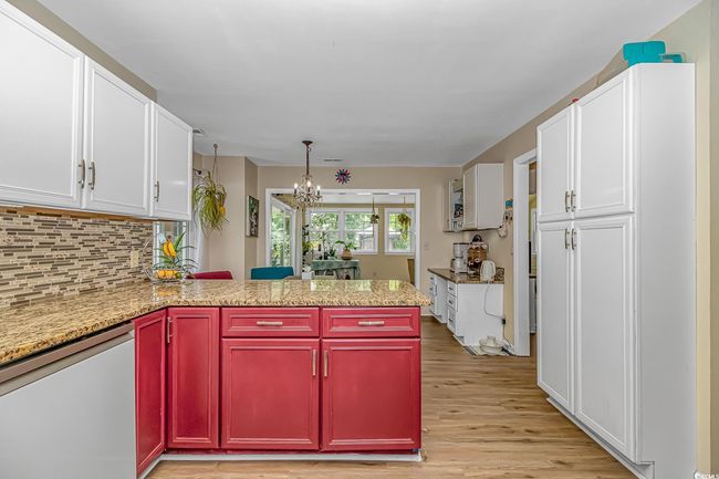 Kitchen with white dishwasher, a chandelier, light wood-style floors, a peninsula, and white cabinetry | Image 12