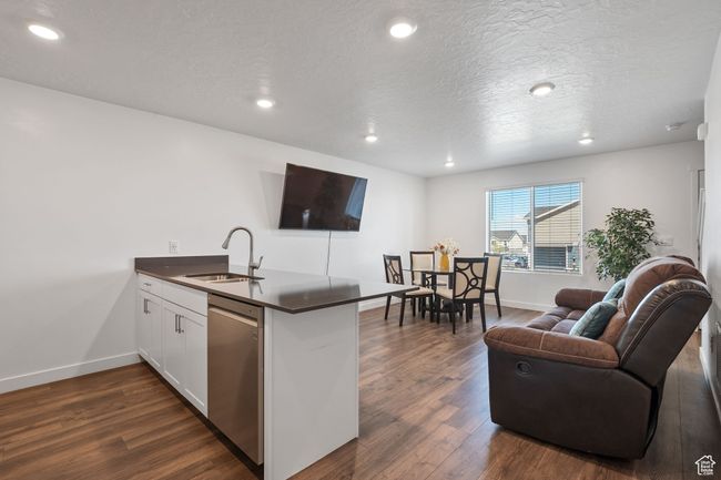 Kitchen with dark countertops, dishwasher, a sink, baseboards, and a peninsula | Image 7