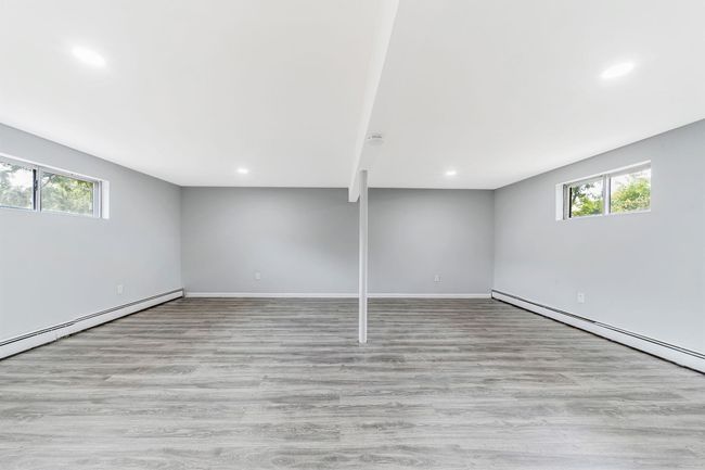 Basement featuring wood finished floors, recessed lighting, a baseboard heating unit, and a wealth of natural light | Image 16