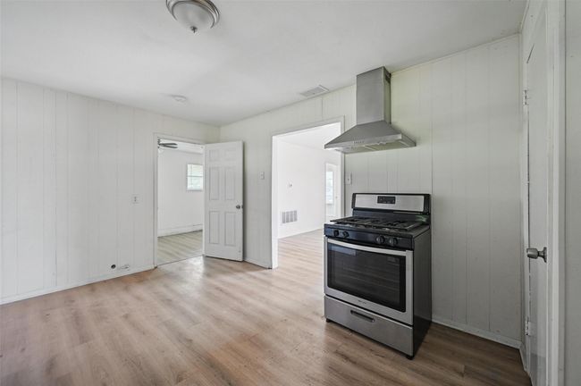 Kitchen with stainless steel gas stove, wall chimney range hood, and wood finished floors | Image 14
