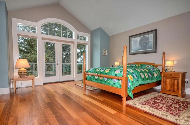 Primary bedroom featuring access to exterior, french doors, high vaulted ceiling, and hardwood floors | Image 13