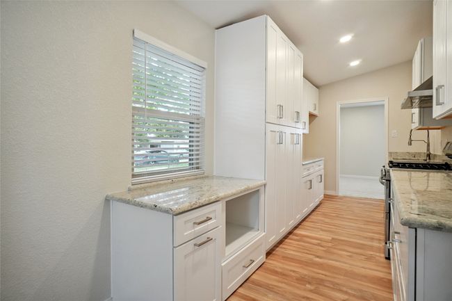 Stunning galley kitchen with custom wood cabinetry, granite countertops, built-in pantry, and upgraded fitxures. | Image 7