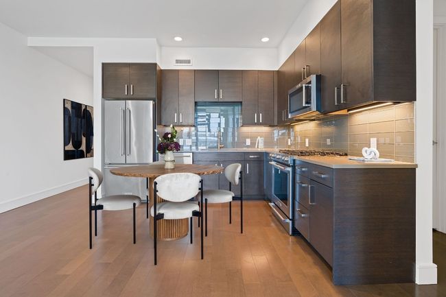 Kitchen with high end appliances, visible vents, dark brown cabinets, and light wood finished floors | Image 8