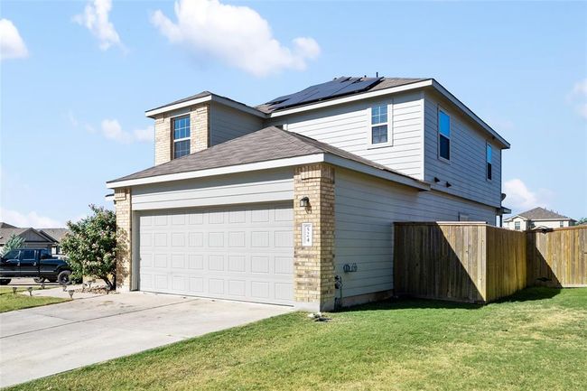 View of side of home featuring roof mounted solar panels, driveway, a garage, and a shingled roof | Image 36