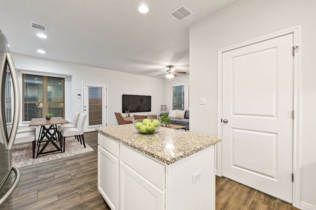 Kitchen featuring visible vents, stainless steel refrigerator, a center island, and dark wood-style flooring | Image 10