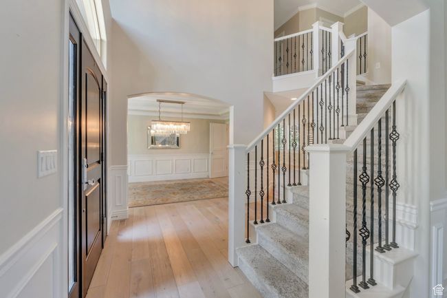 Entrance foyer with arched walkways, a high ceiling, light wood-style flooring, stairs, and ornamental molding | Image 7