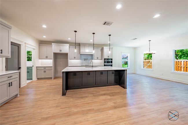 Kitchen featuring hanging light fixtures, sink, a center island with sink, and backsplash | Image 16