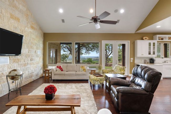 Living room with high vaulted ceiling, ceiling fan, and dark wood-type flooring | Image 12