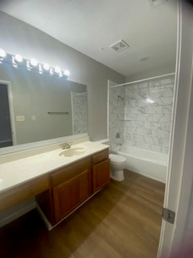 Bathroom with vanity, wood finished floors, washtub / shower combination, and toilet | Image 22