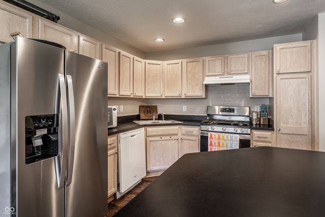 Kitchen with stainless steel refrigerator & stove, lots of cabinets for storage and an island. | Image 9