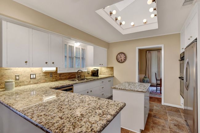 Kitchen featuring a sink, a kitchen island, decorative backsplash, freestanding refrigerator, and white cabinetry | Image 14