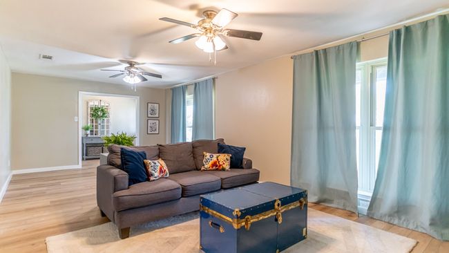 Living area featuring light wood-type flooring, ceiling fan, baseboards, and visible vents | Image 9