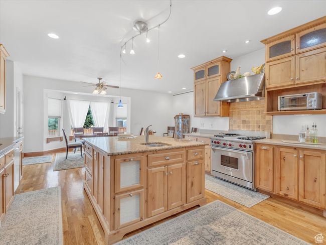 Kitchen featuring luxury stove, light wood-style floors, a sink, and exhaust hood | Image 10