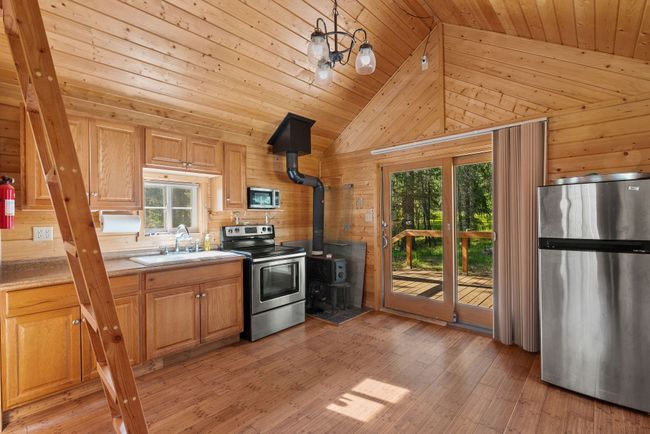 Kitchen area with wood stove & stainless appliances | Image 60