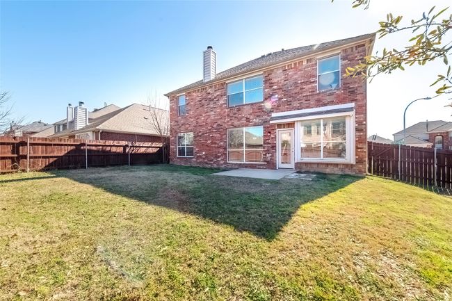 Back of property featuring a fenced backyard, brick siding, a chimney, and a lawn | Image 36