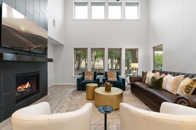 The cozy living room has soaring high ceilings, many windows, and is accentuated by a floor-to-ceiling mock fireplace that's perfect for putting to use during the colder months. | Image 7