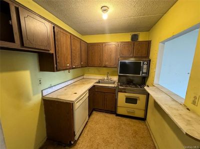 Kitchen featuring white appliances, sink, and light tile patterned floors | Image 3