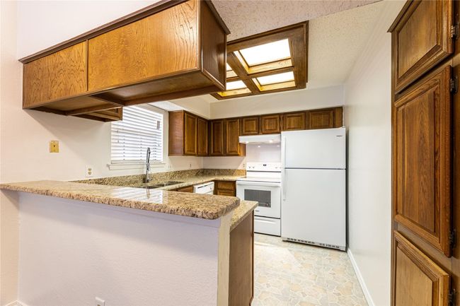 Kitchen with light stone countertops, sink, white appliances, and kitchen peninsula | Image 4