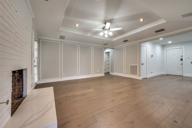 Unfurnished living room with crown molding, ceiling fan, a brick fireplace, hardwood / wood-style flooring, and recessed lighting | Image 9