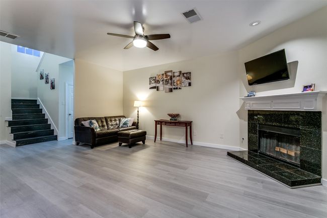Living area with stairway, ceiling fan, wood finished floors, a fireplace, and baseboards | Image 8