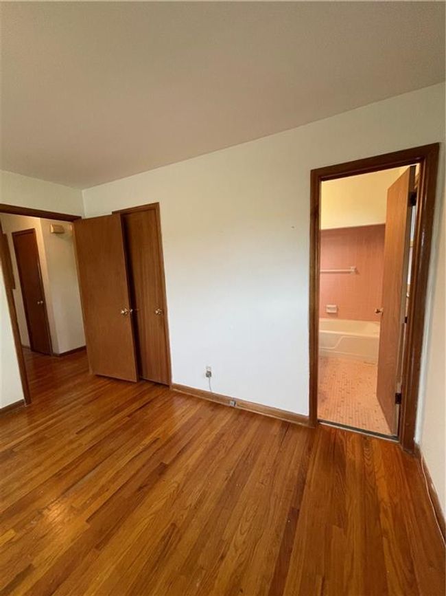 Unfurnished bedroom with wood finished floors, a closet, ensuite bath, and baseboards | Image 17