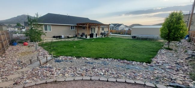 Back of house featuring a trampoline, a fenced backyard, a pergola, and a patio | Image 4