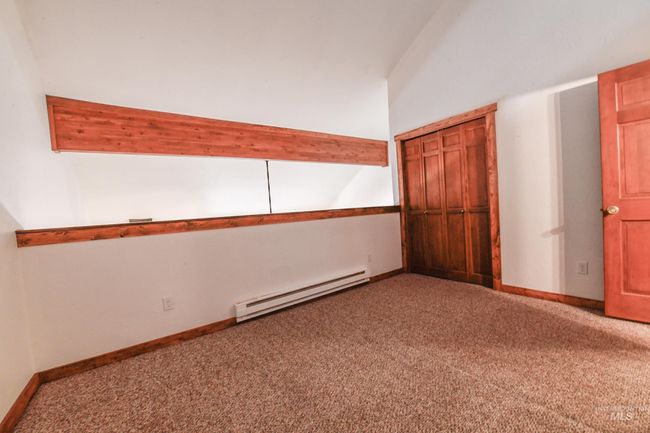Empty room featuring a baseboard heating unit, carpet flooring, and vaulted ceiling | Image 19