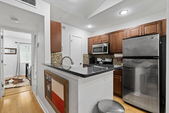 Kitchen with appliances with stainless steel finishes, backsplash, light wood finished floors, a sink, and lofted ceiling | Image 24