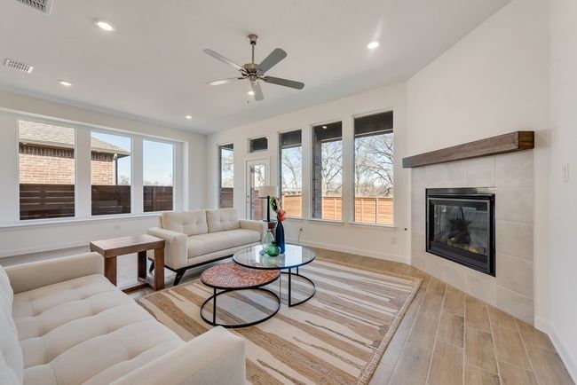 Living area featuring light wood-type flooring, a fireplace, ceiling fan, and recessed lighting | Image 14