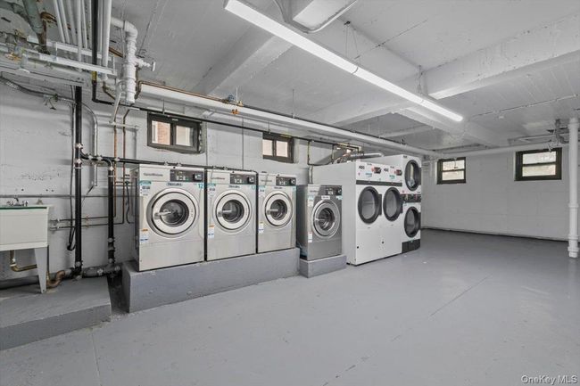 Community laundry featuring washing machine and clothes dryer and concrete block wall | Image 16
