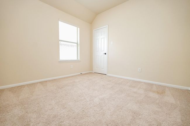 A corner window in a carpeted secondary bedroom offers more wall/floor space for furnishings. | Image 20