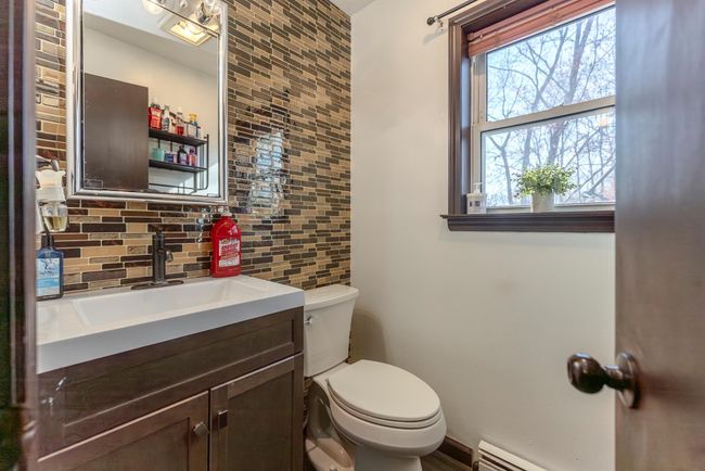 Half bath featuring tasteful backsplash, vanity, toilet, baseboard heating, and tile walls | Image 14