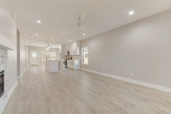 Unfurnished living room with a ceiling fan, a stone fireplace, light wood-style floors, and recessed lighting | Image 6