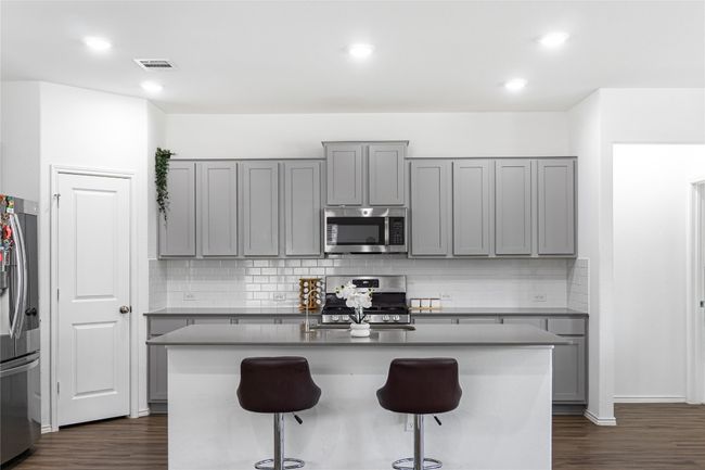 Kitchen with a breakfast bar, visible vents, appliances with stainless steel finishes, and gray cabinetry | Image 9