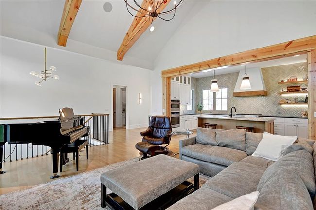 Living area with high vaulted ceiling, a chandelier, beamed ceiling, and light wood-style floors | Image 13