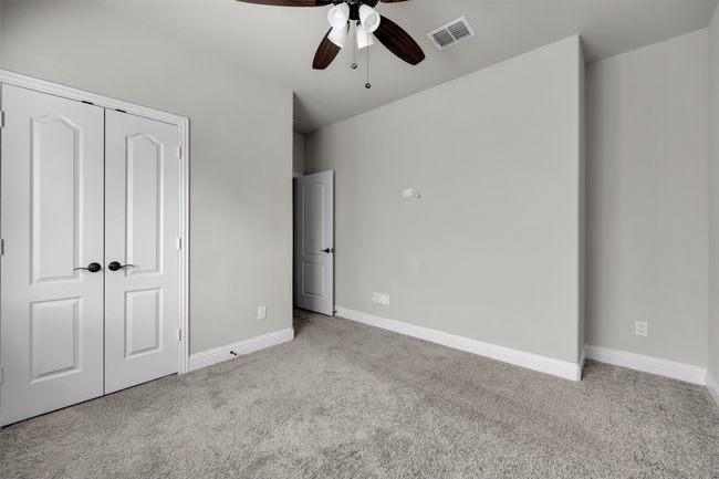 Unfurnished bedroom featuring a walk-in closet, light colored carpet, and ceiling fan | Image 26