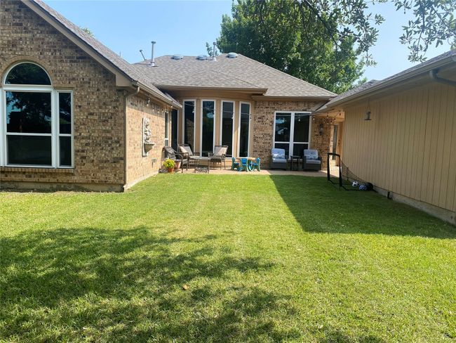Back of property featuring brick siding, a patio area, a yard, and a shingled roof | Image 30