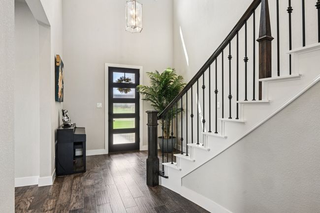 Entryway featuring a high ceiling, stairway, wood finished floors, and a chandelier | Image 6