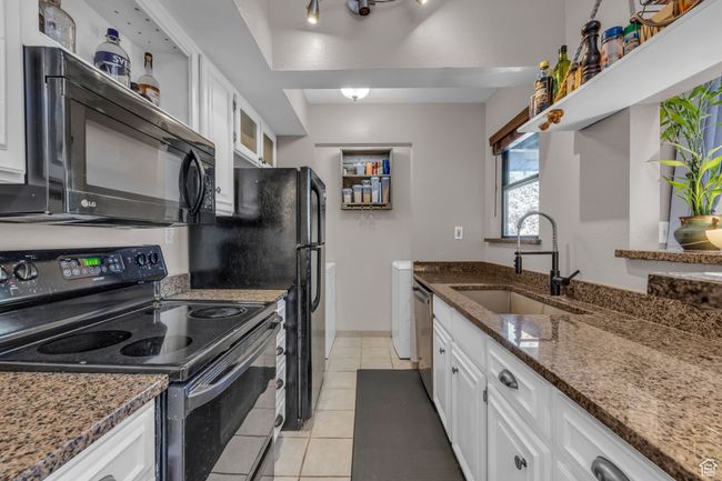 Kitchen with white cabinets, a sink, black appliances, and dark stone counters | Image 6